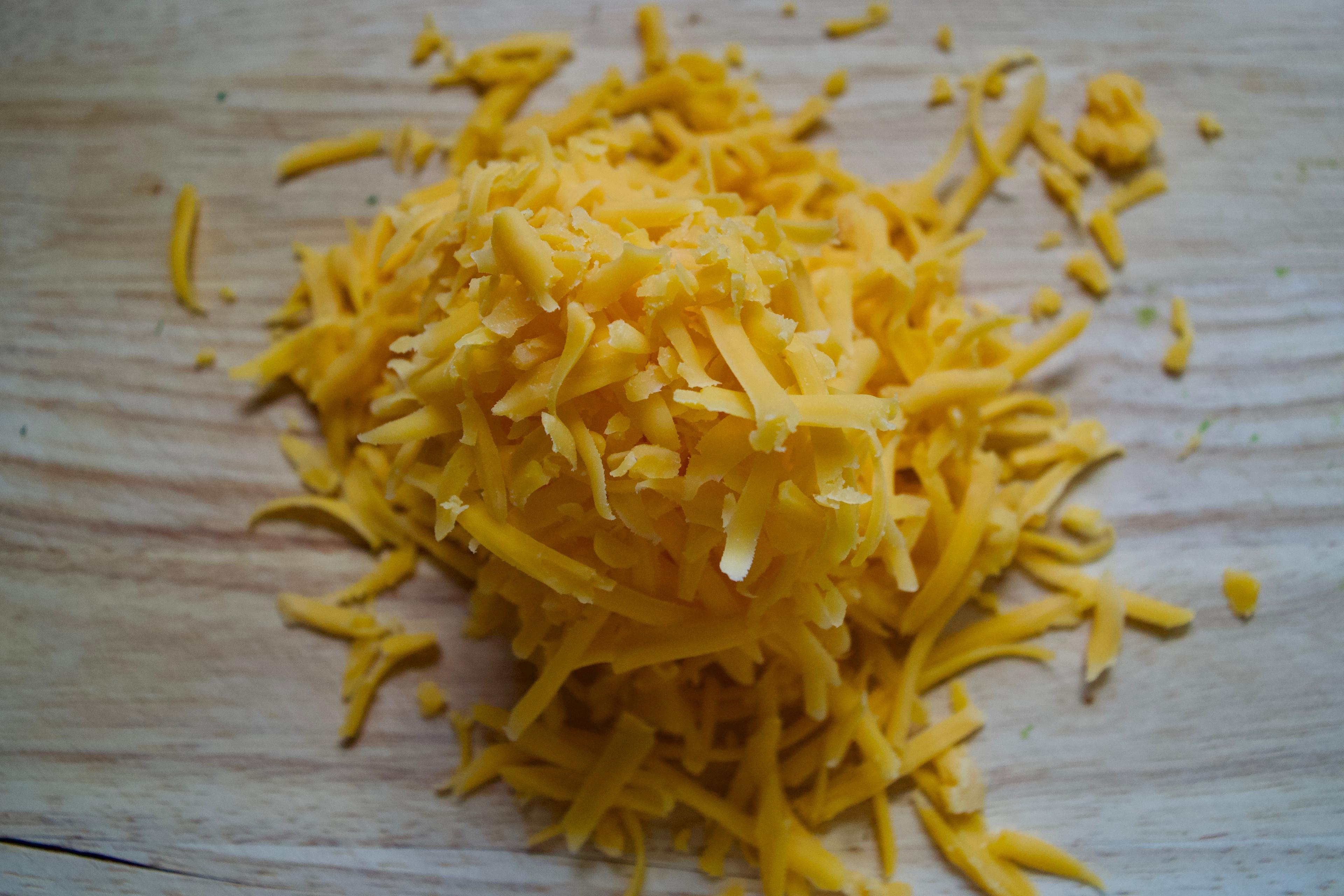 A pile of shredded yellow cheddar cheese