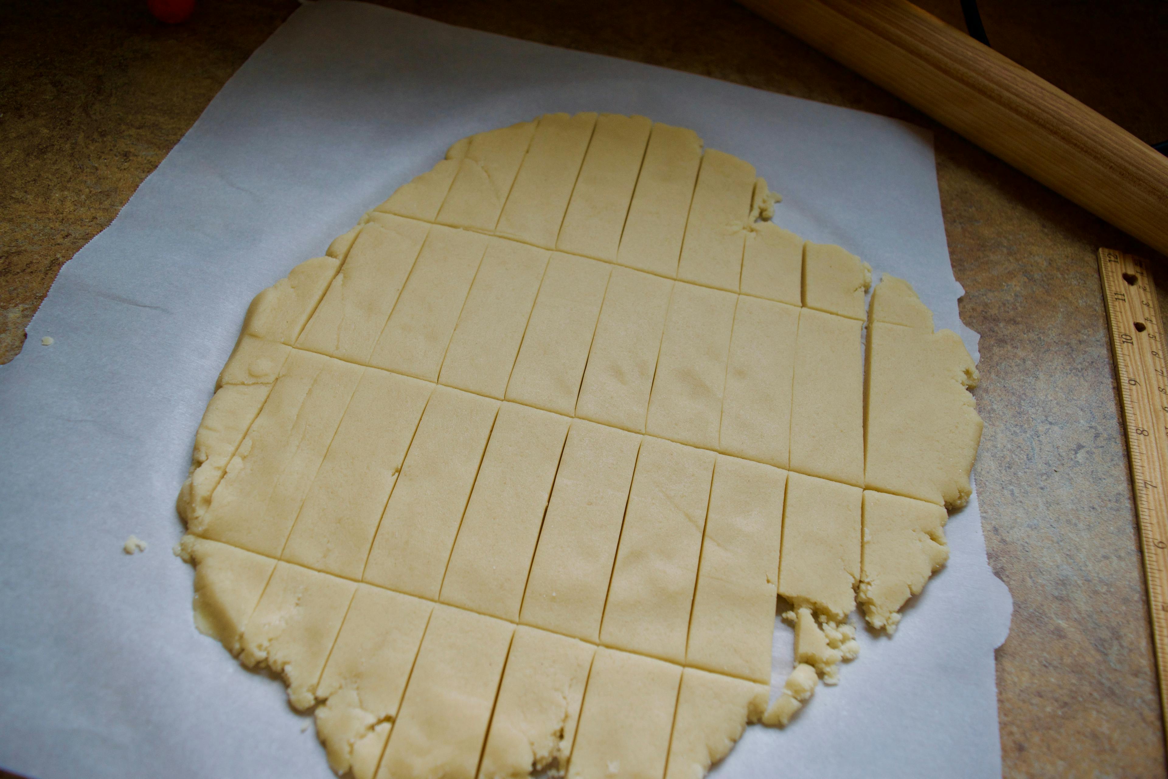 Shortbread dough rolled out thin on parchment paper and cut into rectangles