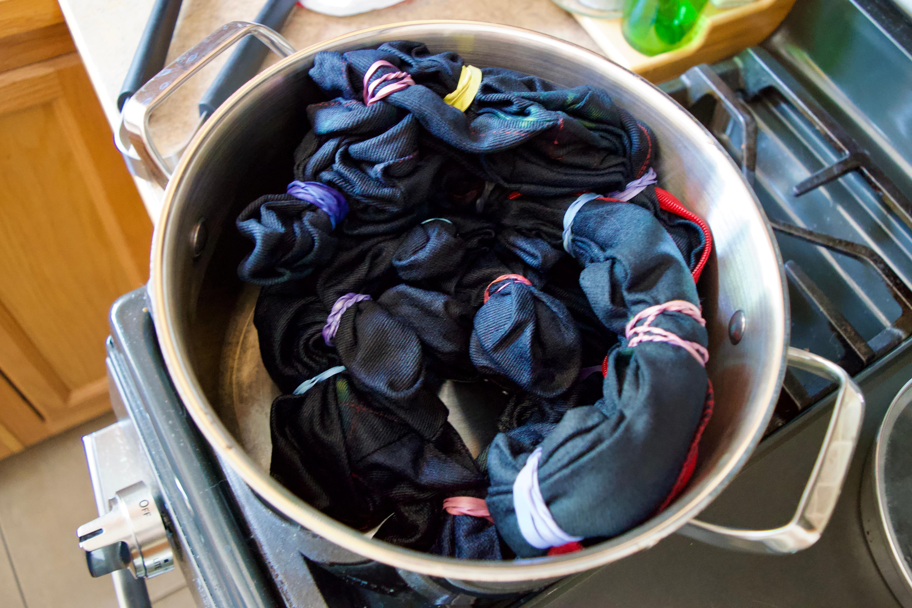 The tied up yoga bolster covers dyed blue, sitting in an empty pot on the stove