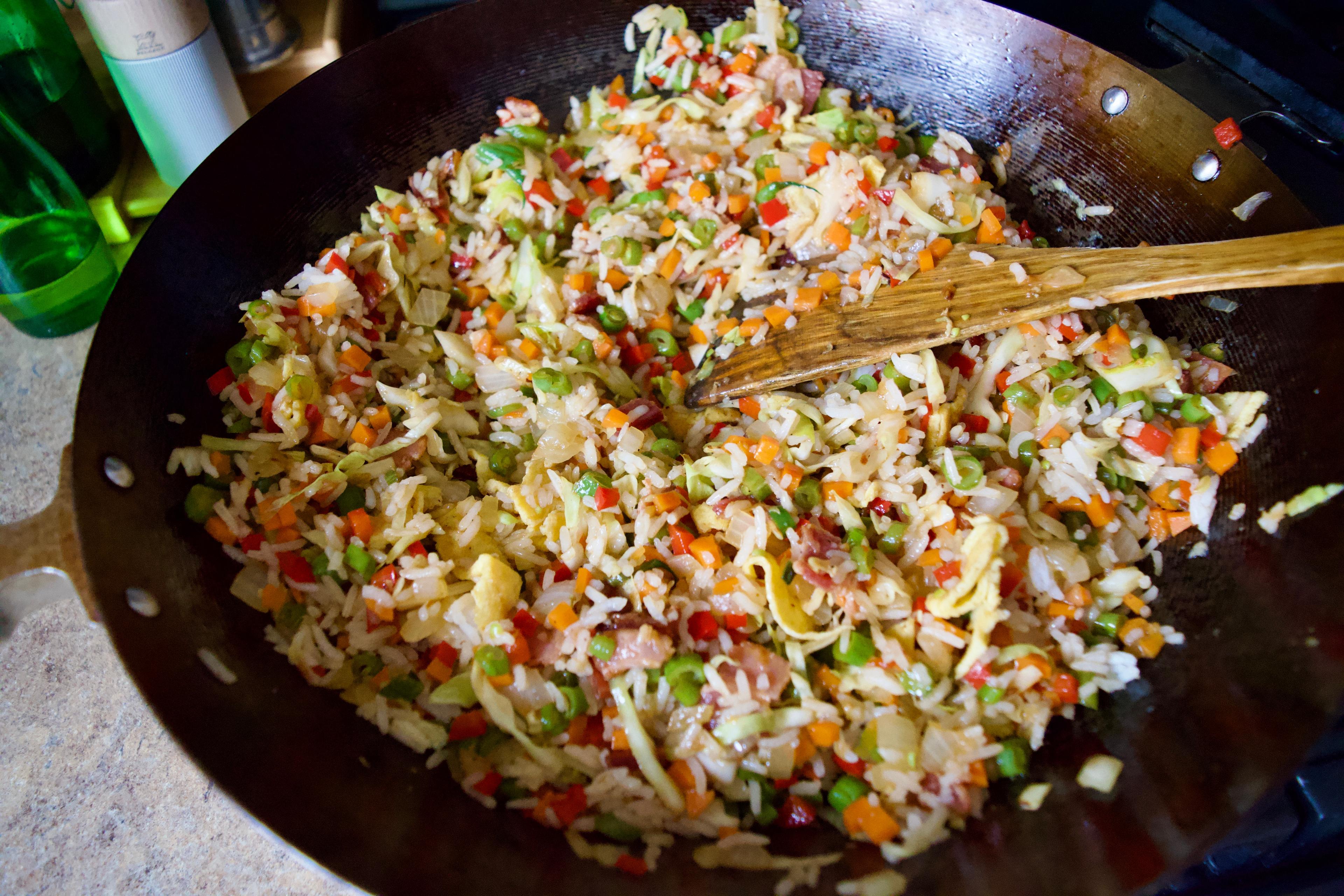 A wok full of bacon and egg fried rice.