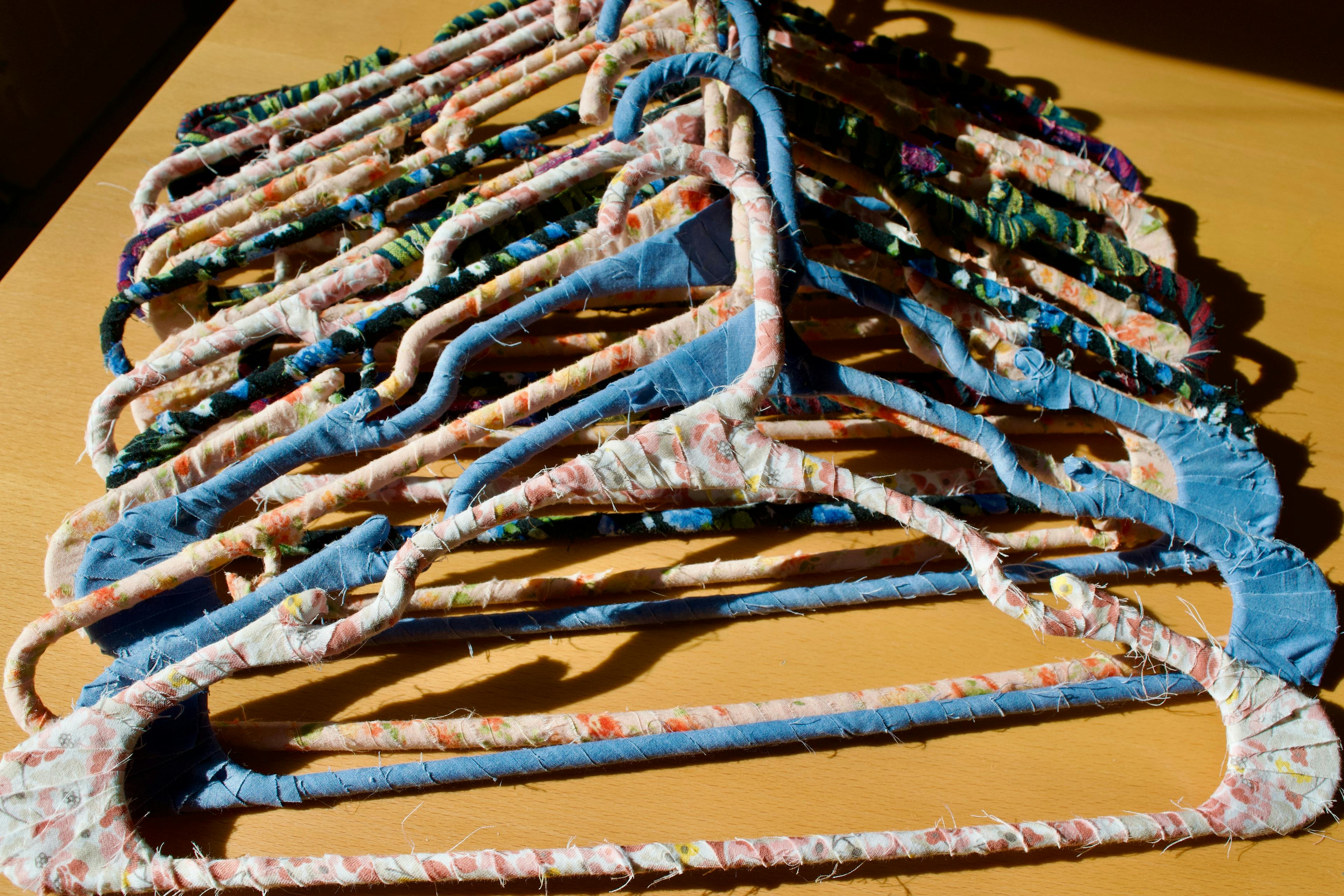A stack of fabric wrapped hangers on a wooden table in bright sunlight