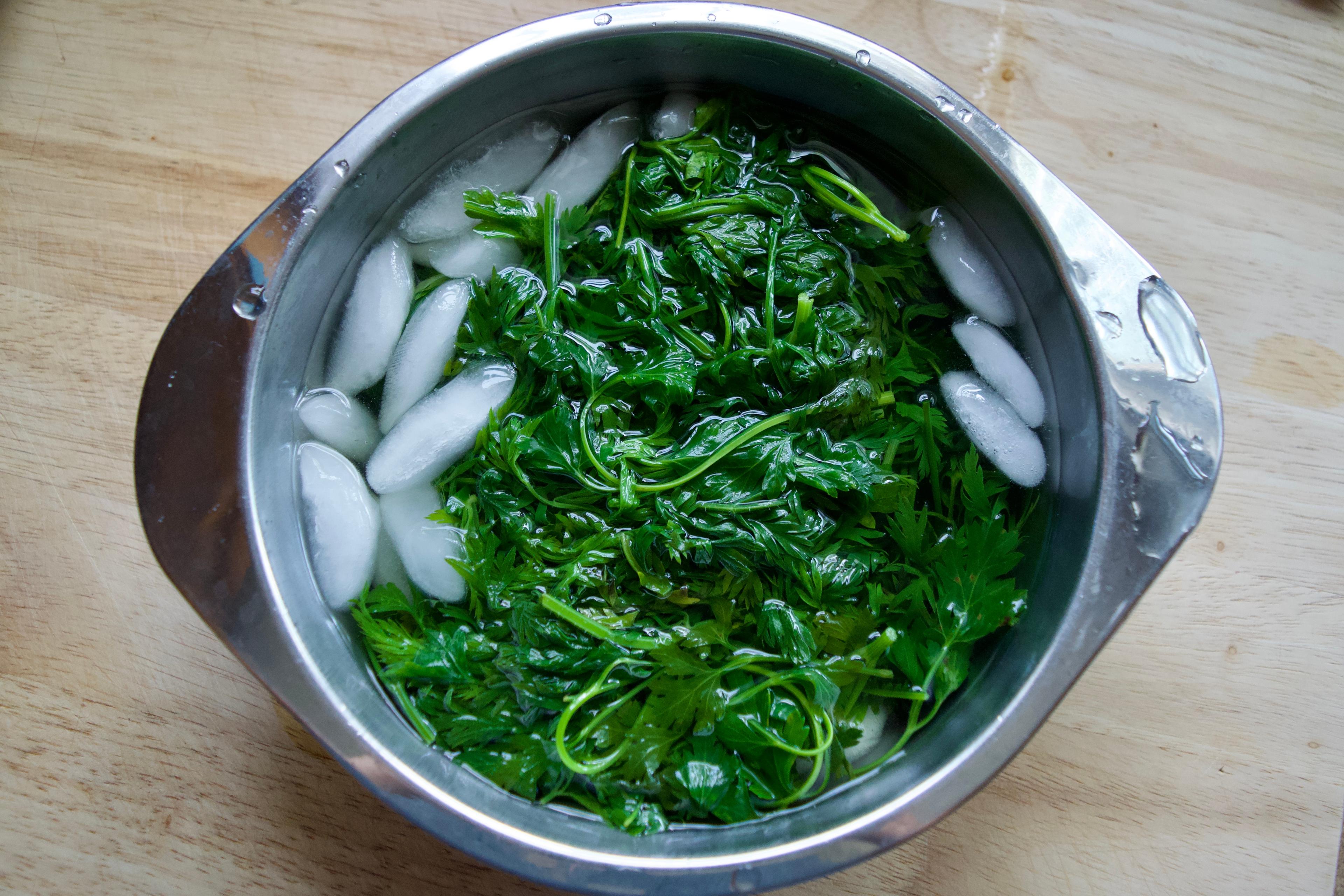 A bowl of blanched greens in ice water.